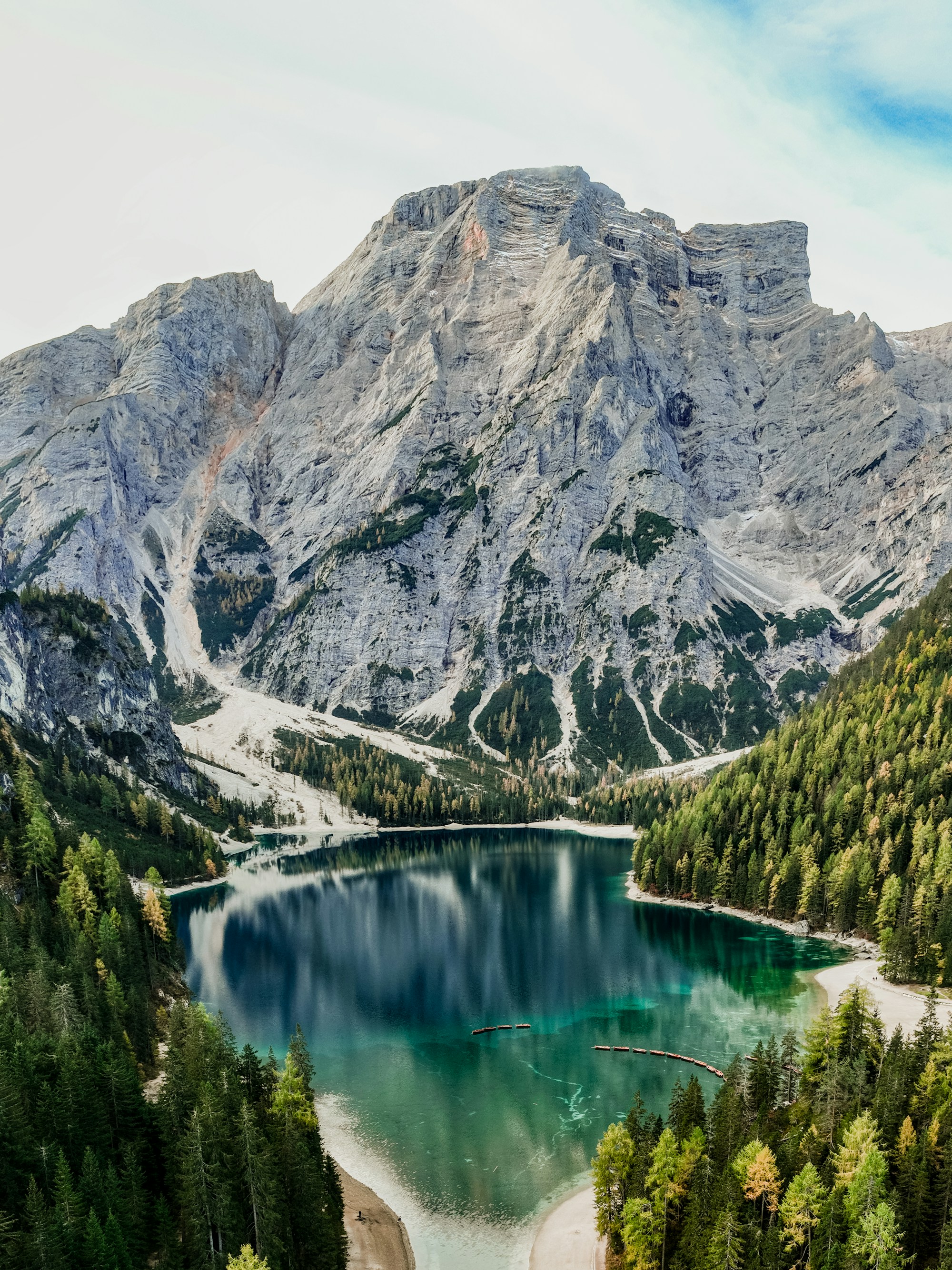 Turquoise alpine lake framed by pine trees and the dramatic peaks of the Dolomites